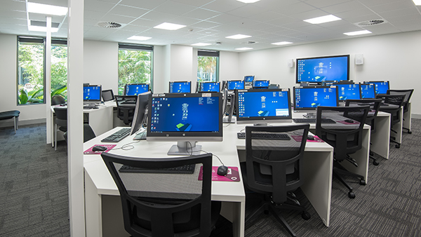 Classroom with multiple computers and desks for students to learn and work.