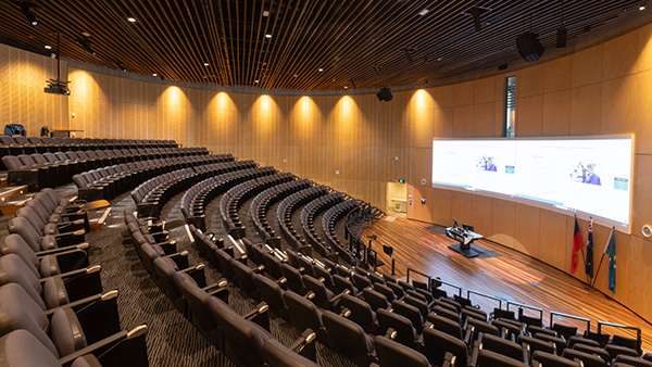 Large auditorium with rows of chairs and a projector screen for presentations or lectures.