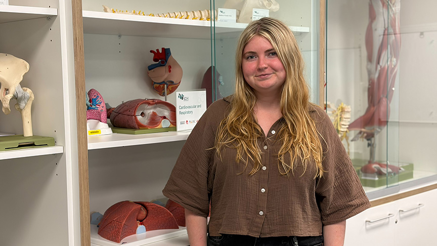 A woman stands in front of a display showcasing various anatomy models in a well-lit educational setting.