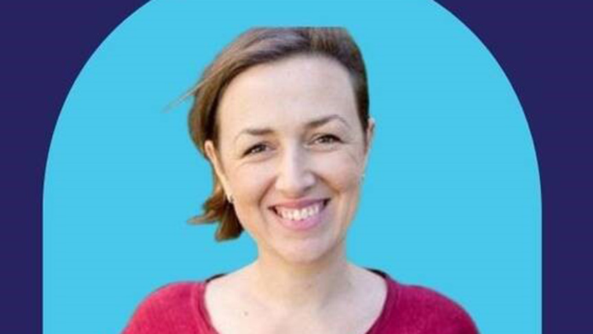 A woman smiling against a vibrant blue background, exuding warmth and positivity.
