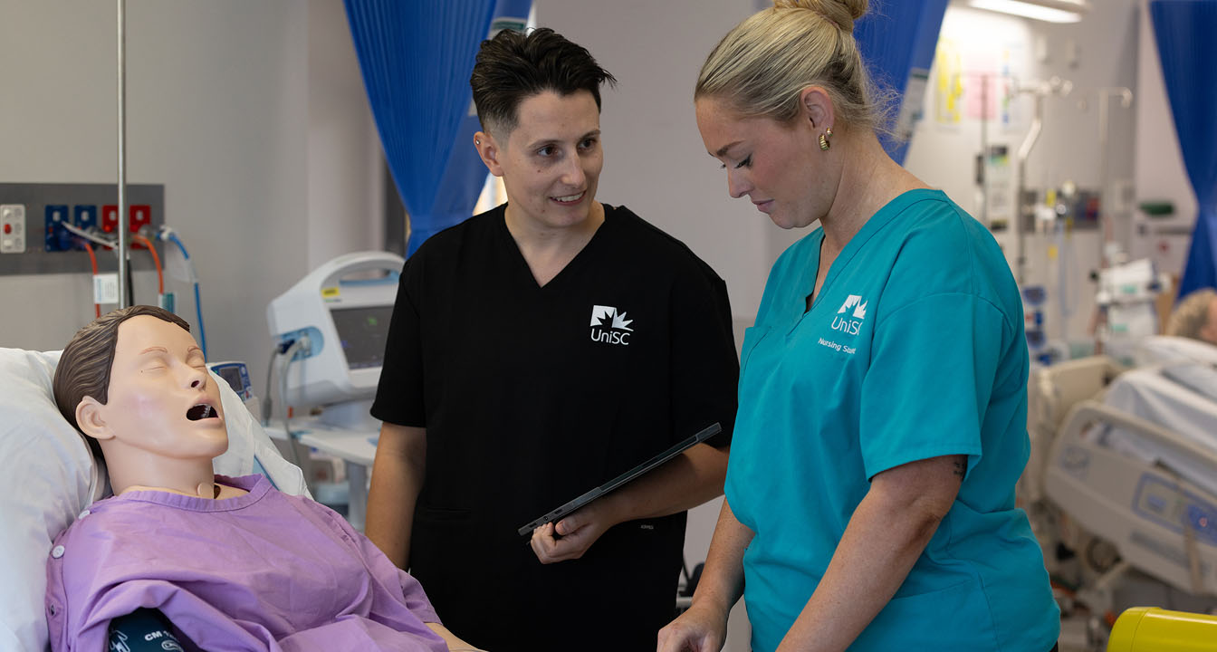 Nursing instructor teaching a student with a medical dummy
